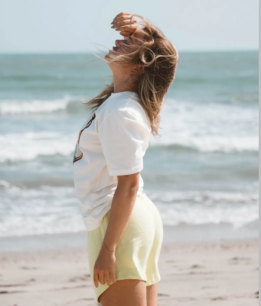 Una mujer de espaldas al mar, con el pelo al viento, en la arena de Preá
